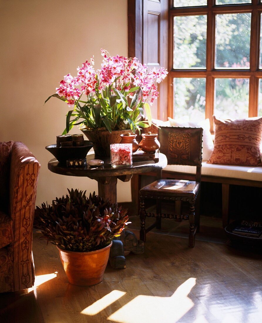 Sitzecke vor Sprossenfenster mit Bank & Blumenarrangement auf rundem Holztisch