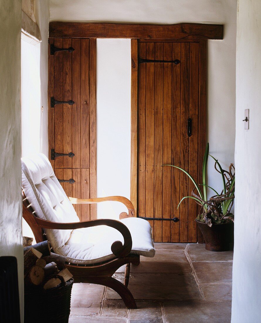 Flurbereich eines Landhauses mit rustikalen Holztüren, Steinfussboden & Holzstuhl mit Polsterauflage
