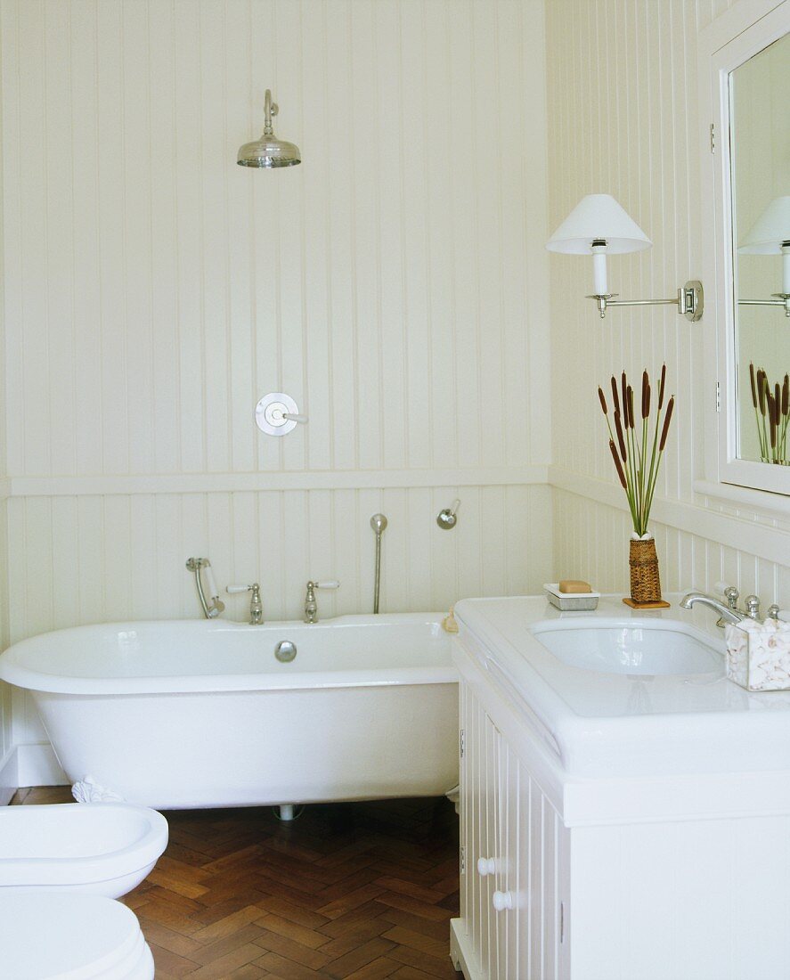 Weisses Bad im Landhausstil mit Waschtisch, Badewanne & holzverkleideten Wänden