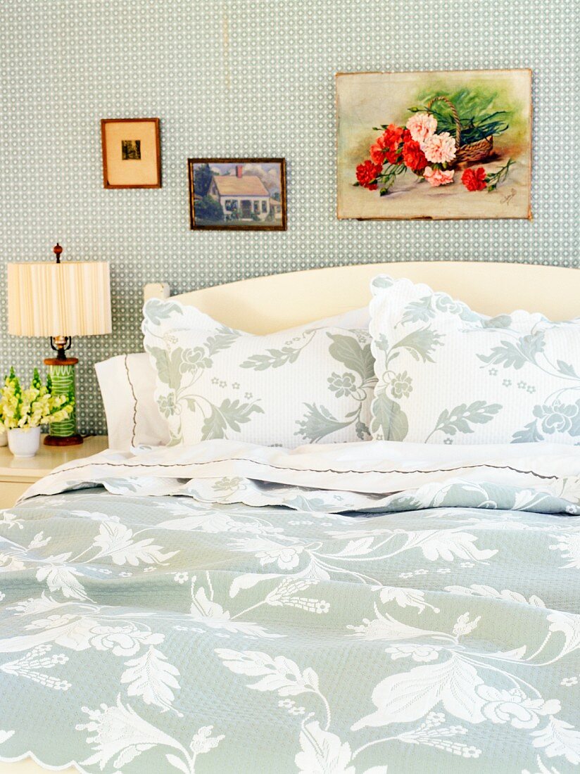 Doppelbett mit Kopfteil und Bettwäsche mit floralem Muster in Weiß und Hellgrau