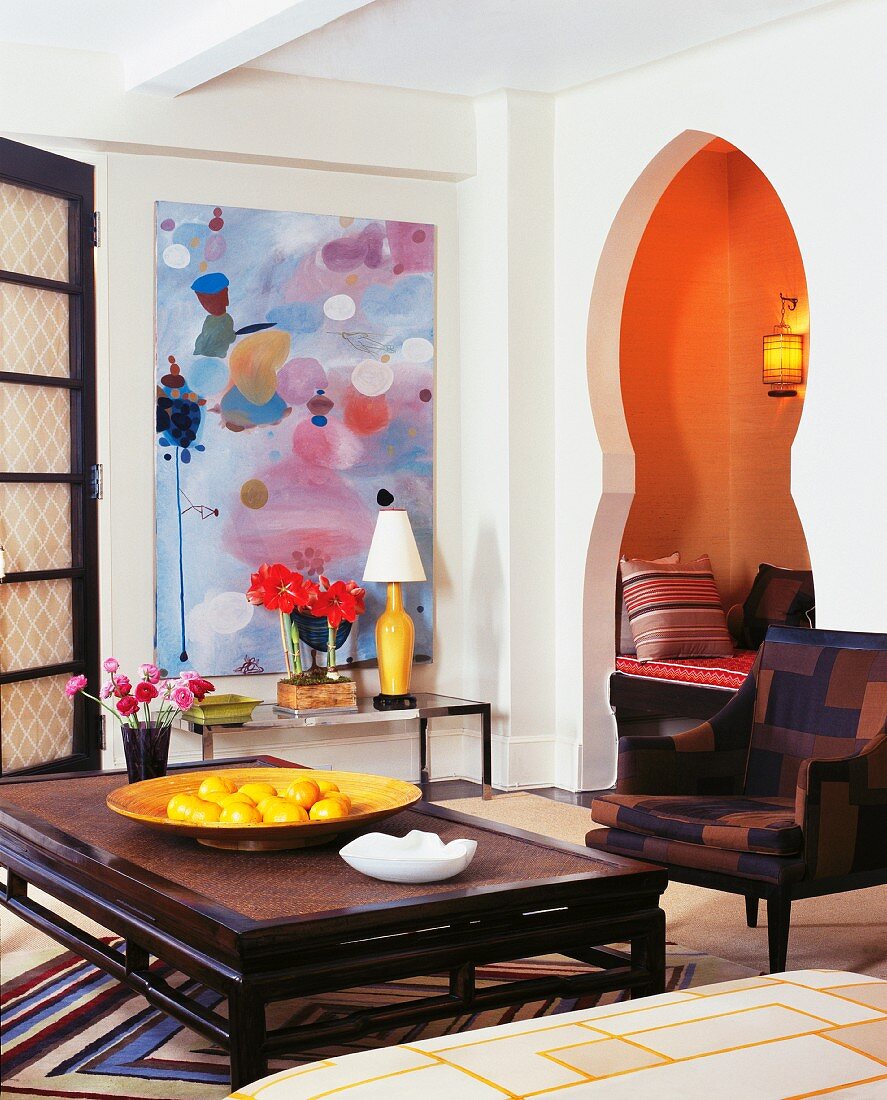 Couchtisch aus dunklem Holz in asiatischem Stil und Sessel in modernem Wohnzimmer mit geschwungenem Türausschnitt in maurischem Stil