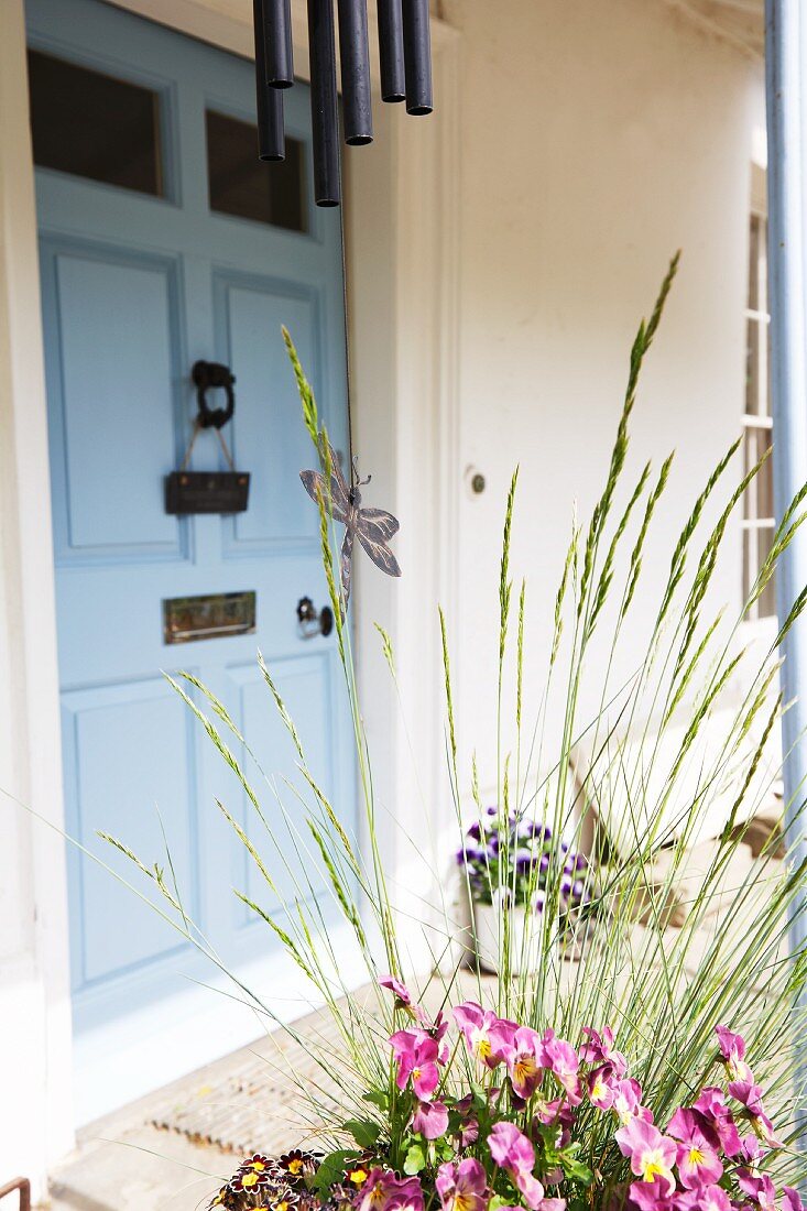 Eingangsbereich mit blauer Tür, Windspiel & Blumendeko