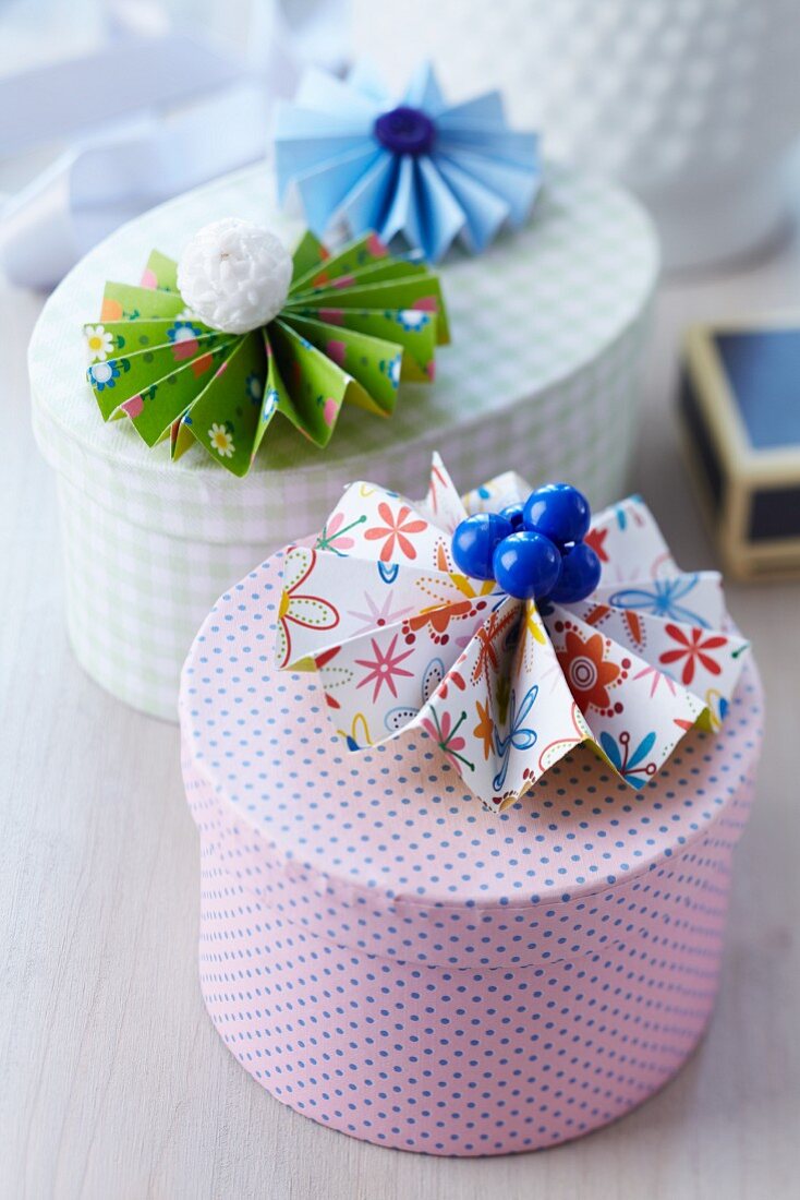 Bunte Papierrosette mit Knöpfen als Dekoration auf verschiedenen Geschenkpackungen