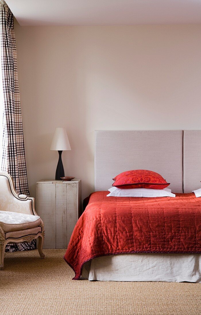 Naturtöne mit kräftigem Rot im Schlafzimmer - Holzkiste als Vintage Nachttisch und modernes Doppelbett mit gesteppter Tagesdecke