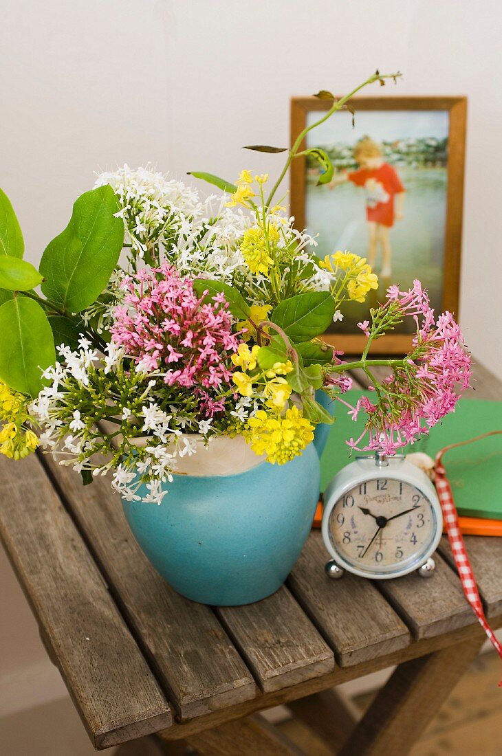 Improvisierter Nachttisch - Vase mit Wiesenblumen und Retro Wecker auf Holzklapptisch