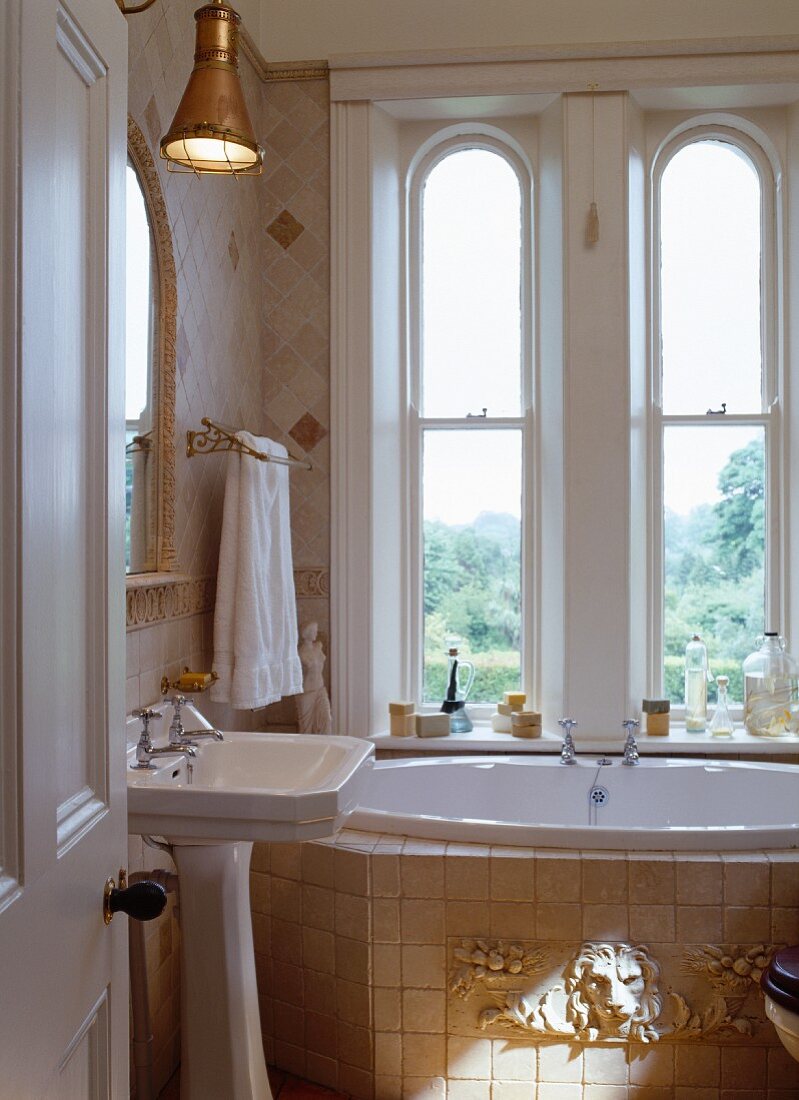 Kleines Bad im Antikstil mit Säulenwaschbecken und unter Fenster eingebaute Badewanne