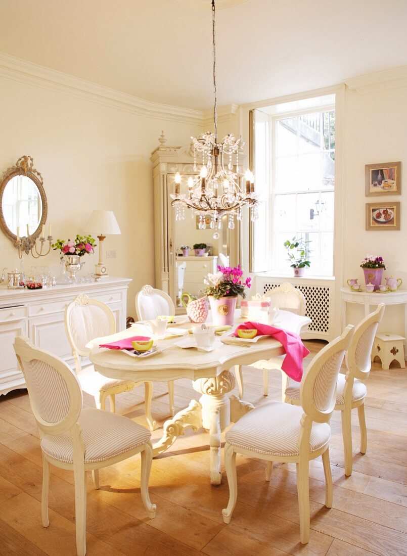 Weisses Esszimmer mit Tisch und Stühlen im Neo-Rokokostil unter Kronleuchter