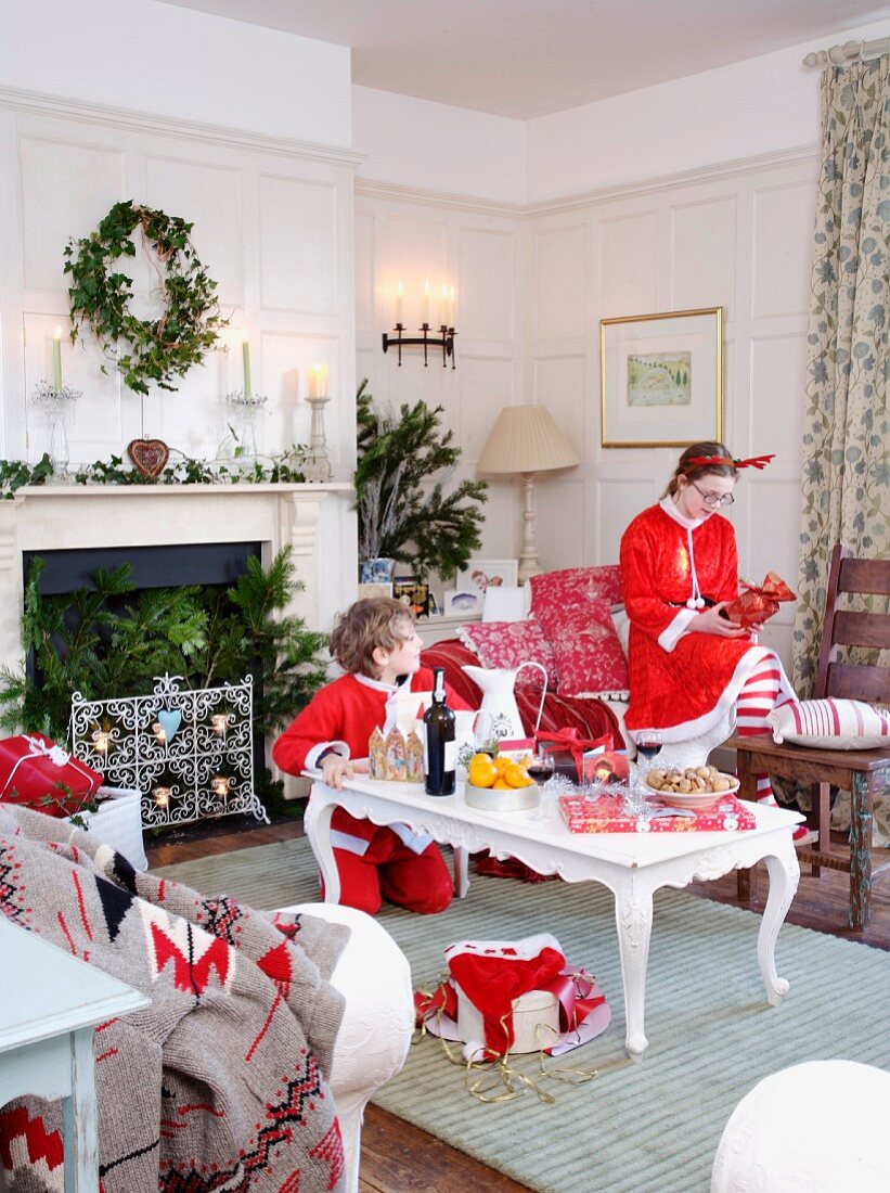 Kinder mit Nikolaus-Anzügen in weihnachtlich dekoriertem Wohnzimmer