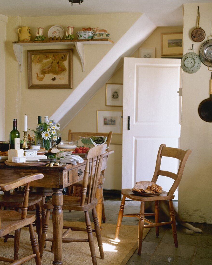 Gedeckter, rustikaler Esstisch aus Holz mit Holzstühlen in Landhausküche