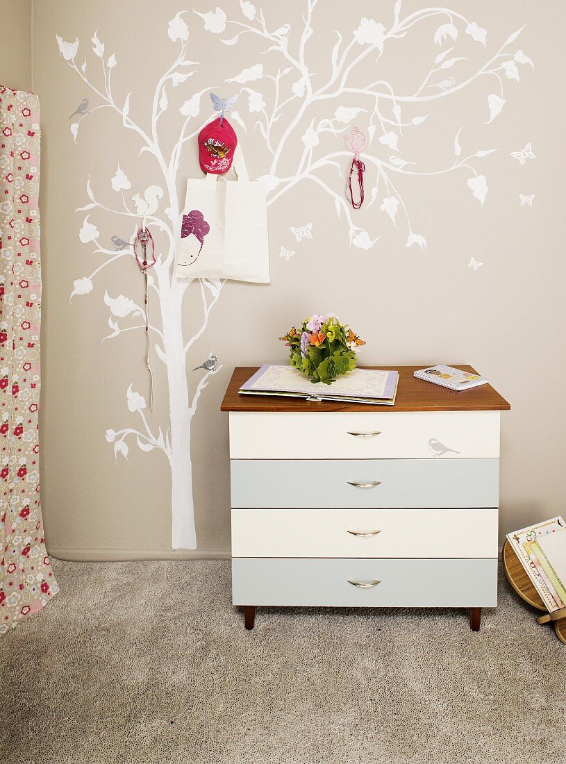 Chest of drawers and painted tree with coat hooks in teenager's bedroom