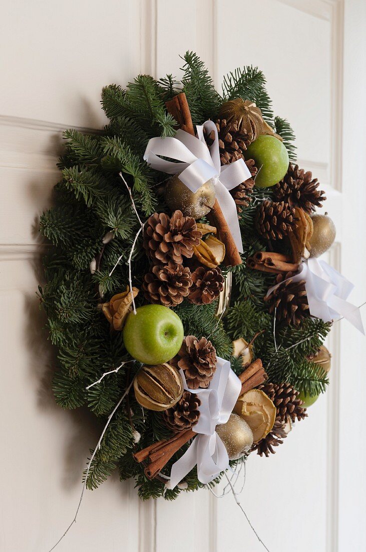 Wreath with festive decorations on white front door