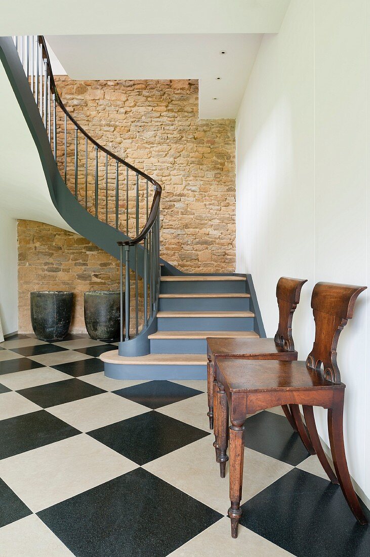 Elegant gewendelter Treppenaufgang einer umgebauten Scheune mit naturbelassenem Sichtmauerwerk