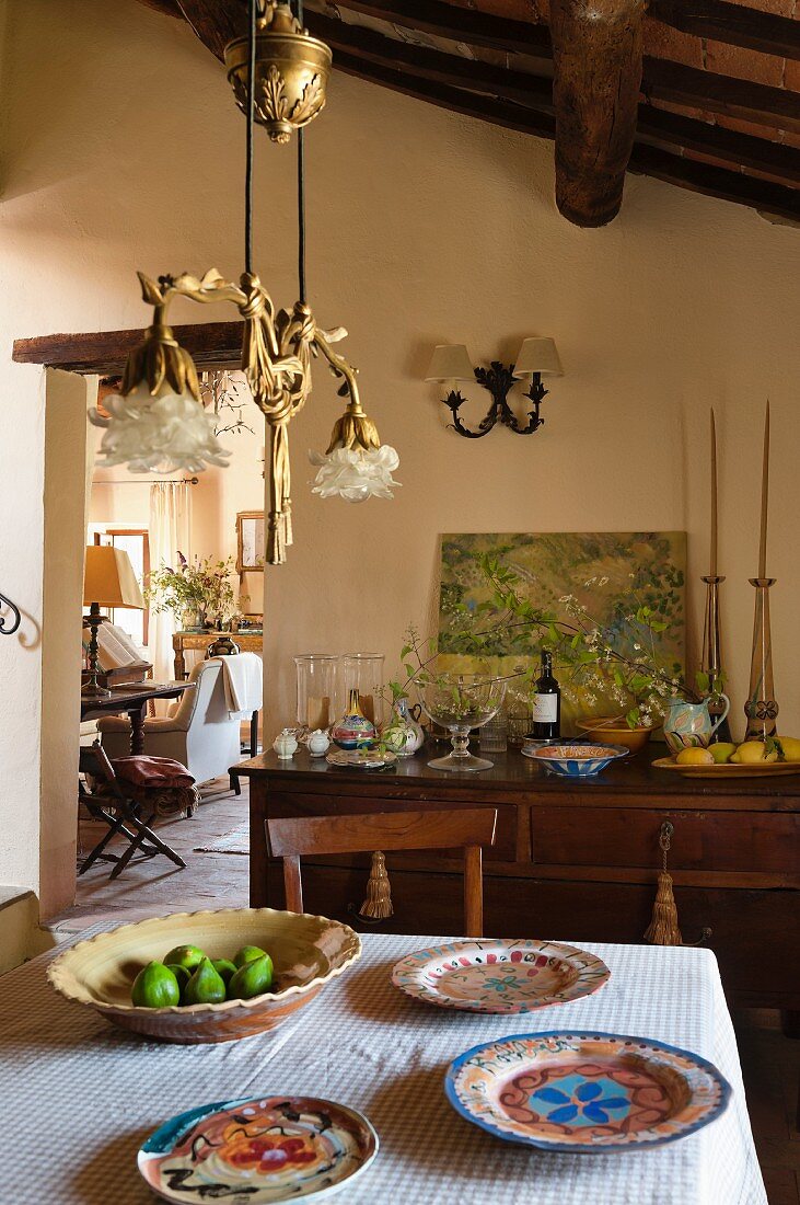 Landhausambiente mit dekorativer Pendelleuchte und bemaltem Geschirr im offenen Wohnbereich
