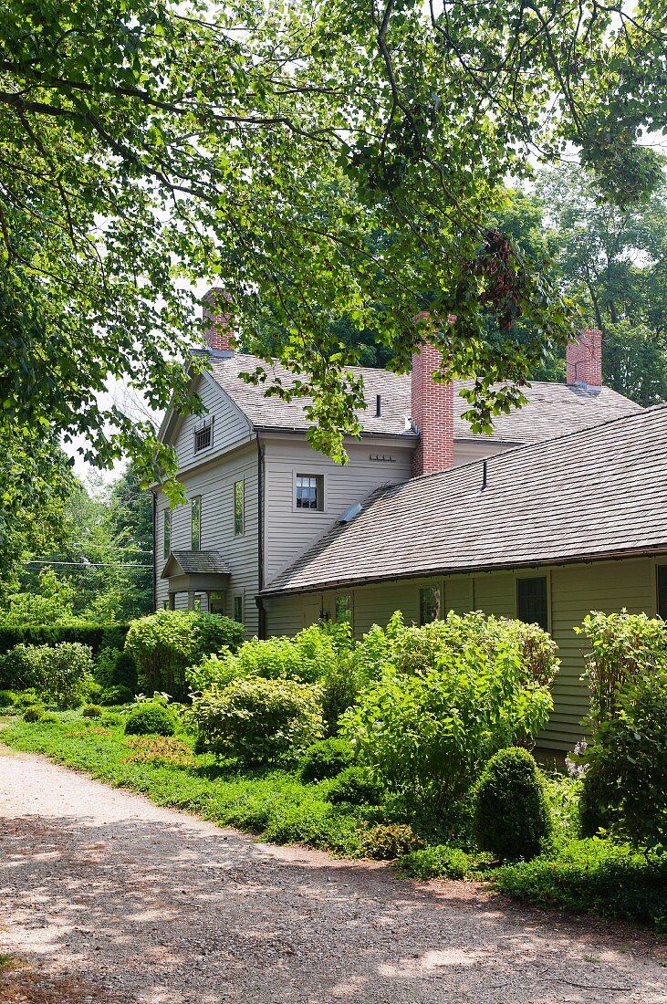 Georgianisches Wohnhaus in Massachusetts mit gekiester Zufahrt und sommerlichen grünen Büschen
