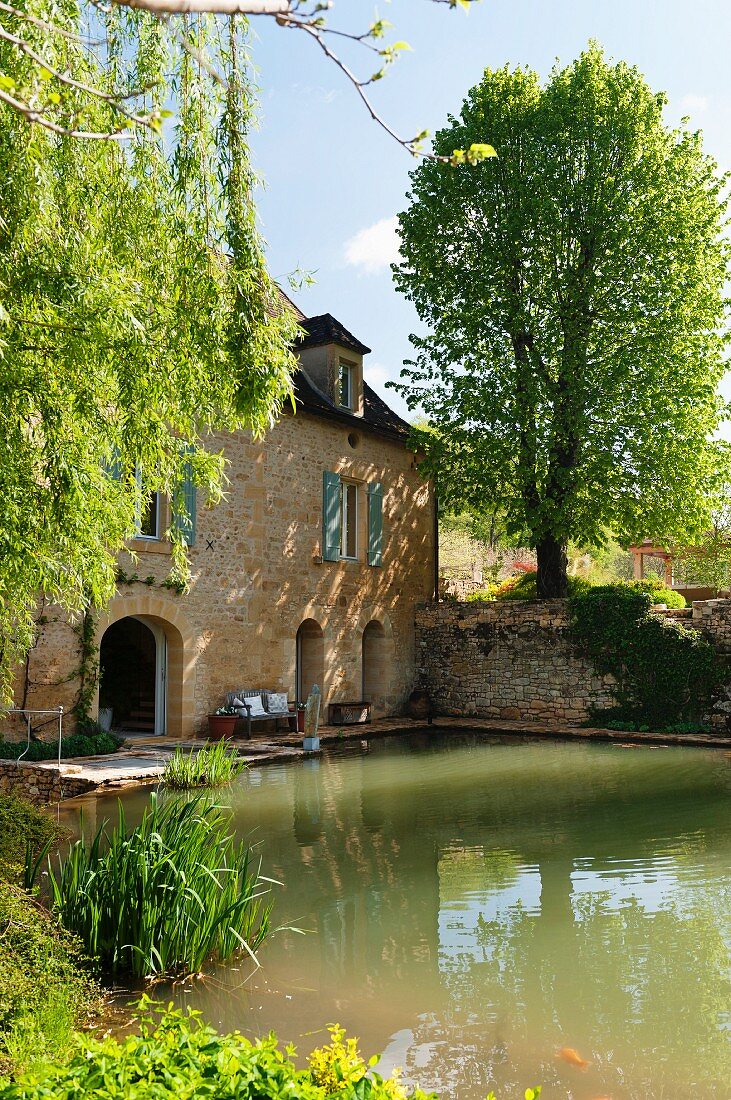 Teich vor historischem Mühlengebäude in der Dordogne