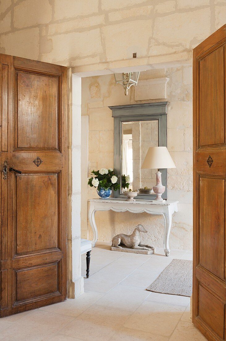 View through double doors of console table and mirror in foyer of Proven