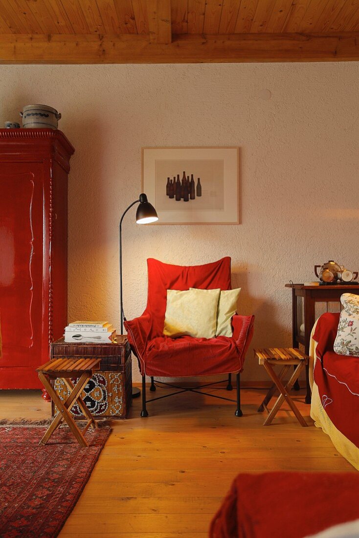 Seating area in shades of red with chair, sofa & cupboard in village house (Eggelingen, Ostfriesland, Germany)