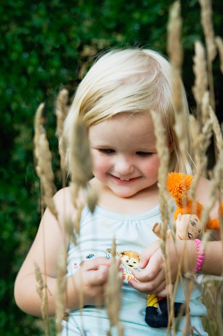 Lächelndes kleines Mädchen mit Puppe im Arm