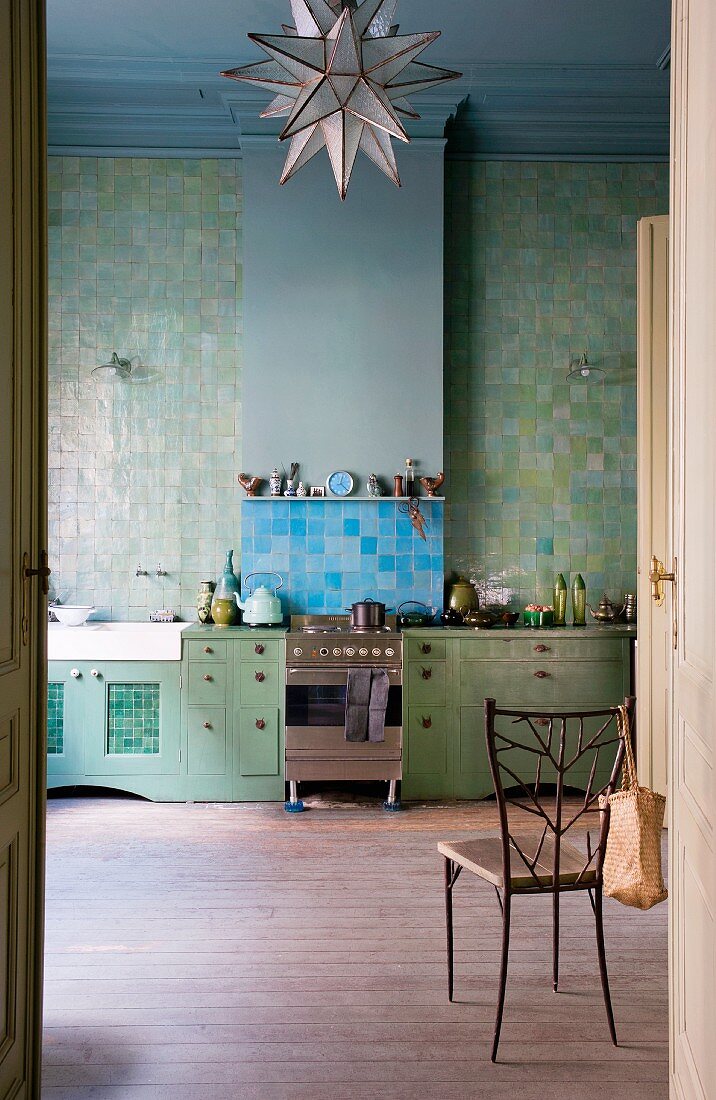 View of green kitchen counter below green tiled wall through open door
