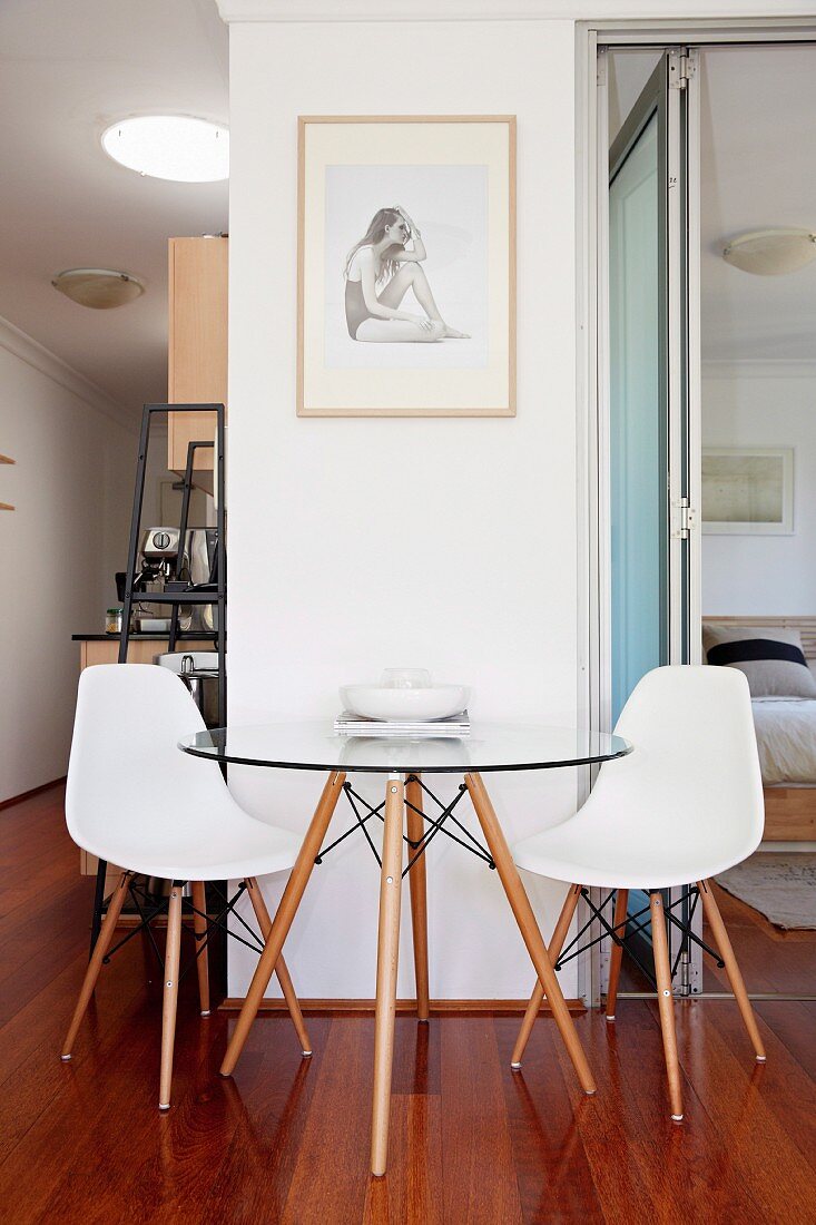 Sitzplatz vor Wandpfeiler mit Designermöbeln auf edlem Parkett; Einblick in den Schlafbereich und auf der anderen Seite in den Küchenbereich