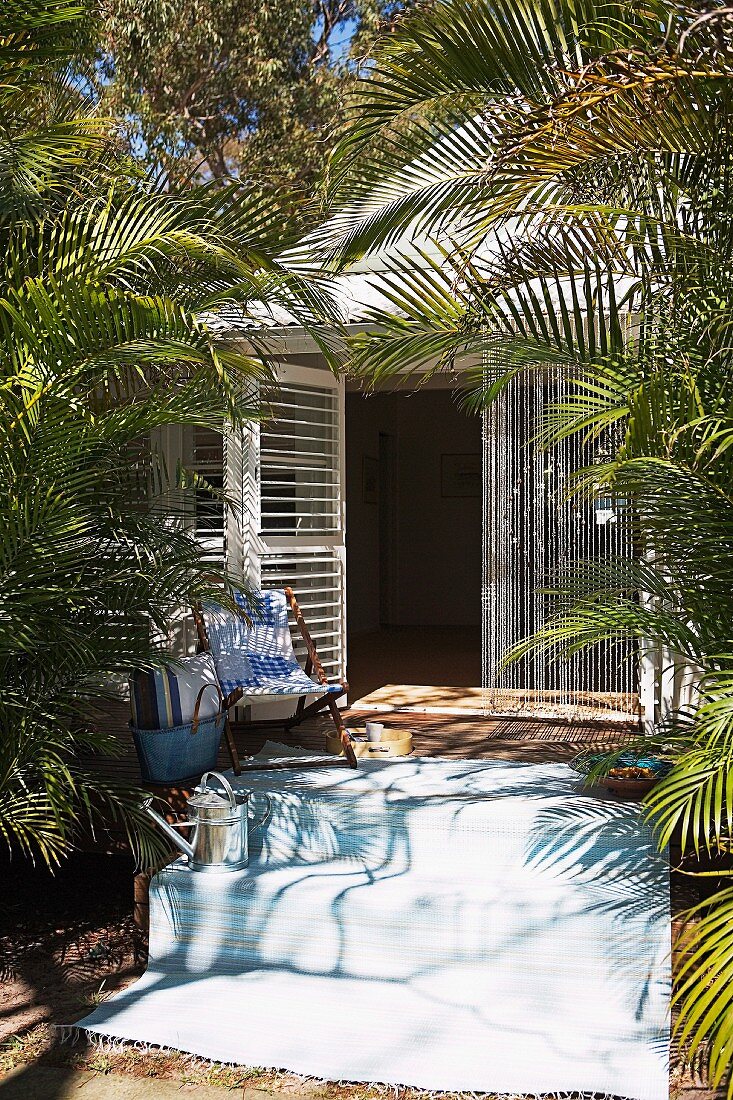 White summer house in sunshine surrounded by palm trees