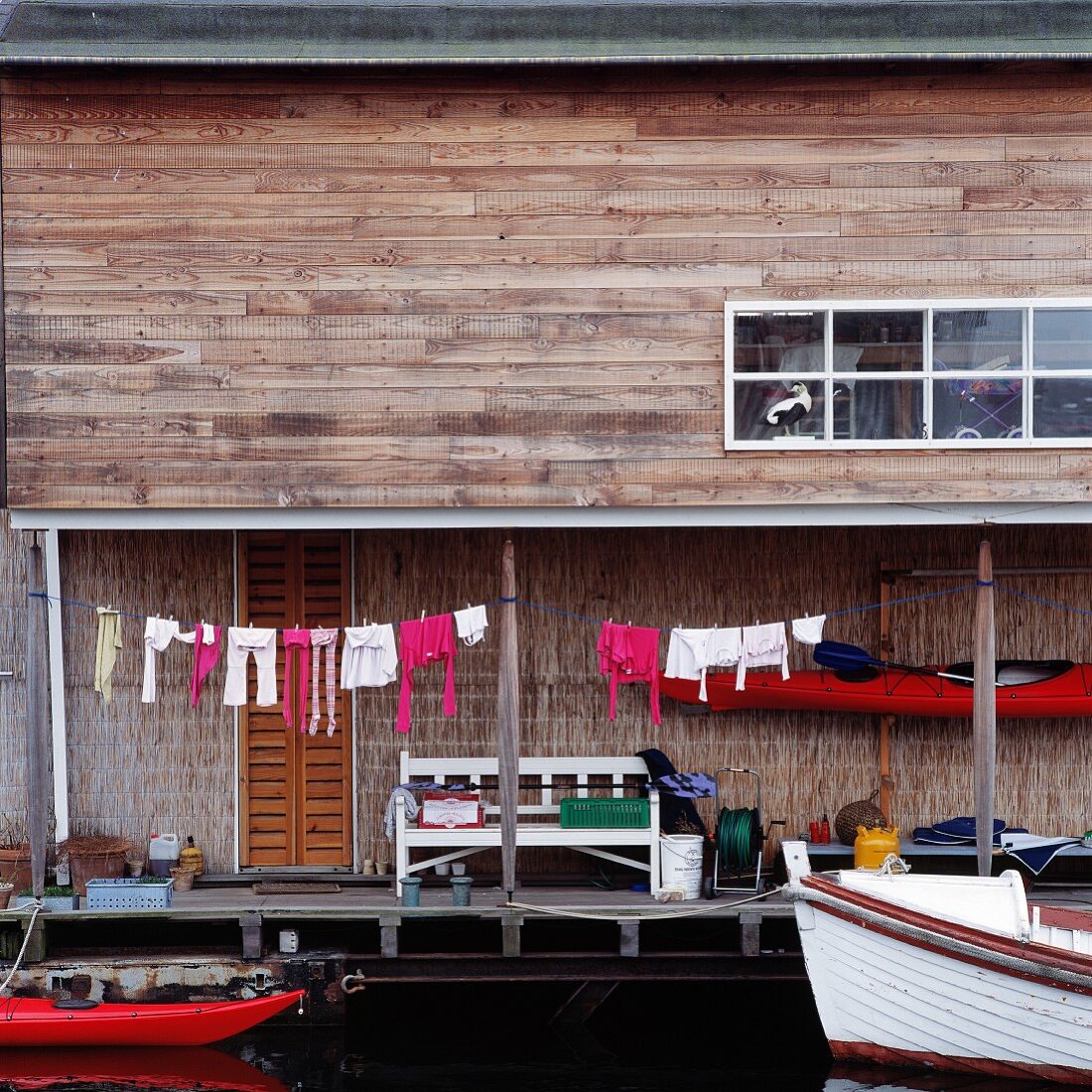 Wooden house with laundry hanging to dry and moored boats on lake shore