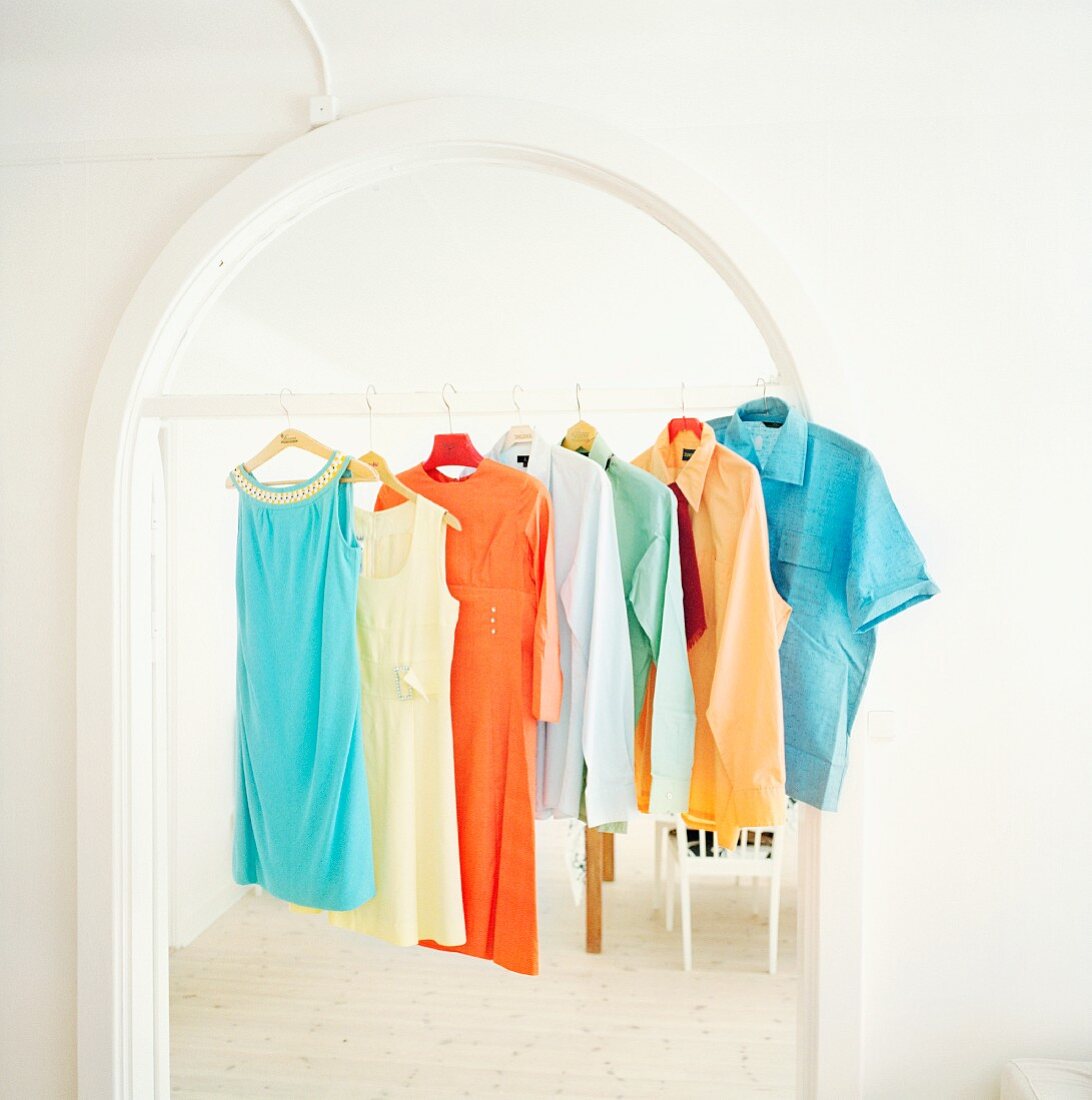 Colourful shirts and dresses hanging on frame of arched doorway