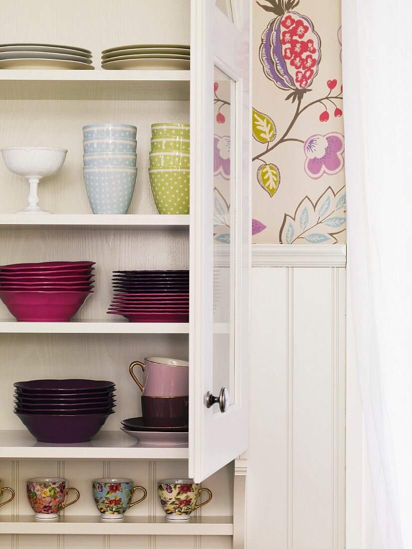 Colourful crockery in white cupboard
