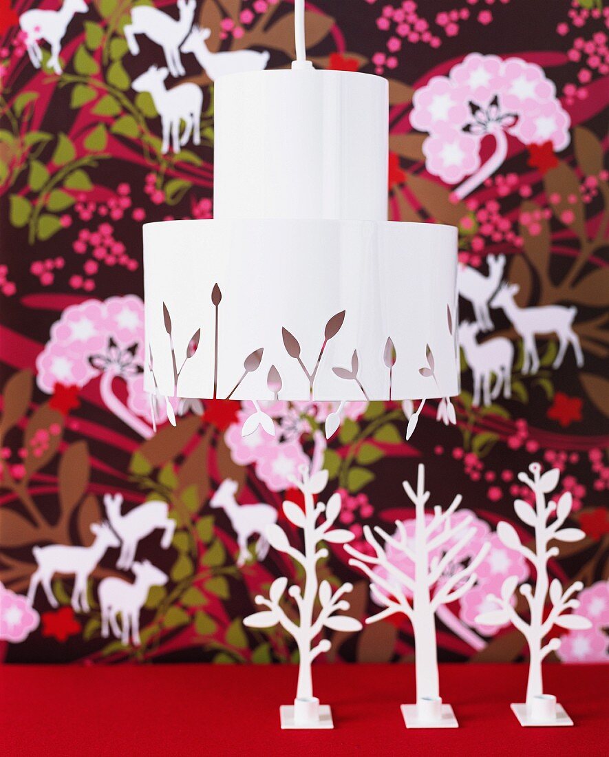 White lampshade with pattern of leaves against floral wallpaper