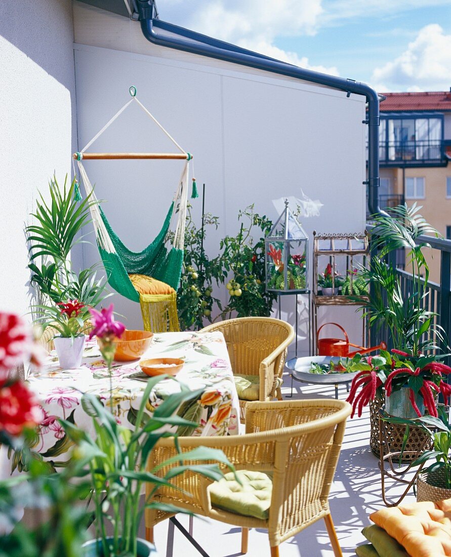 Frühlingsstimmung auf Balkon - Gemütlicher Sitzplatz mit Rattanstühlen und Blumentöpfe