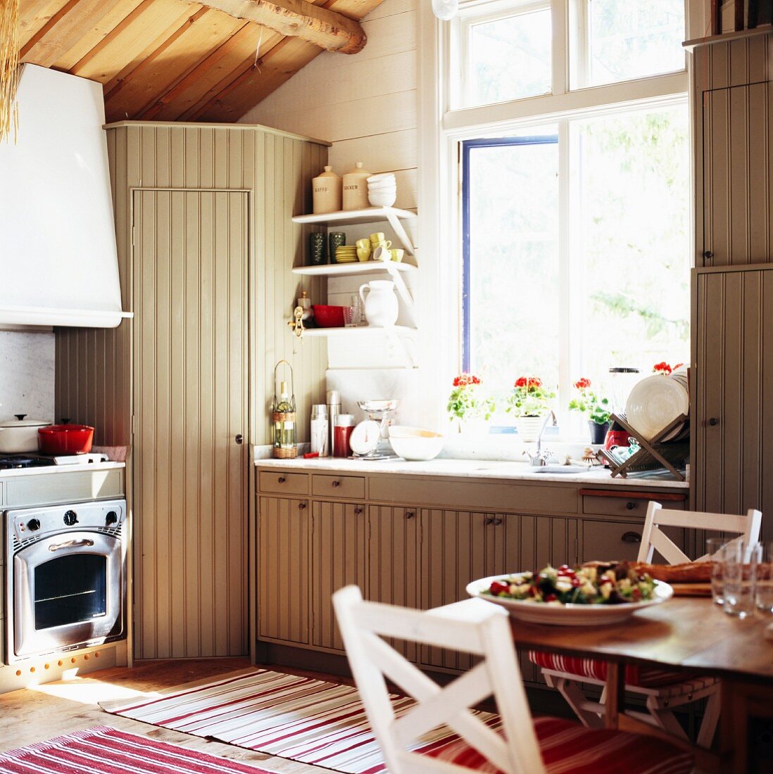 Einbauküche im Country-Style mit Holzfronten unter rustikaler Dachkonstruktion
