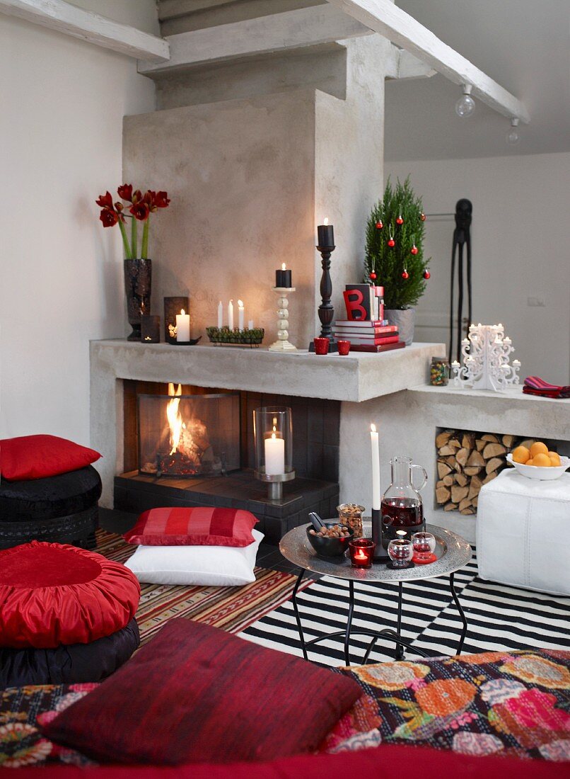 Weihnachtsdeko auf modernem Kamin mit Raumteilerfunktion; Sitzecke mit Bodenkissen und Tabletttisch
