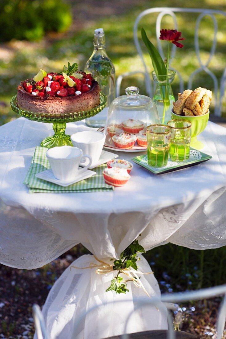 A table in a garden ready laid with cake and buns, Sweden.