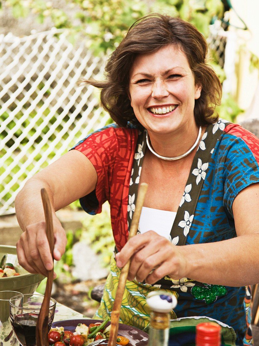 Woman serving salad, smiling, portrait
