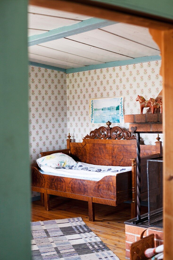 Blick durch offene Tür auf antikes Bett mit Seitenwand in ländlicher Schlafzimmerecke