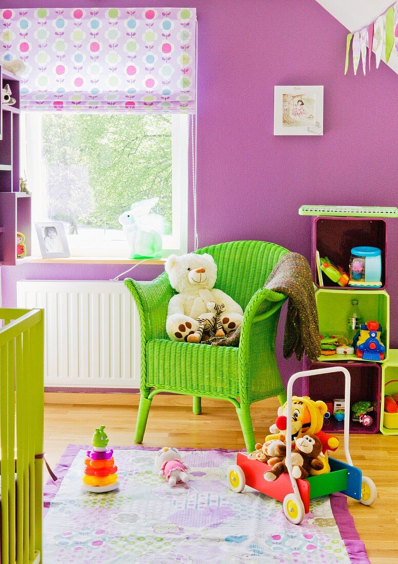 Bunte Kinderwelt - Lindgrüner Korbstuhl mit Stofftier vor Fenster in violett getöntem Kinderzimmer