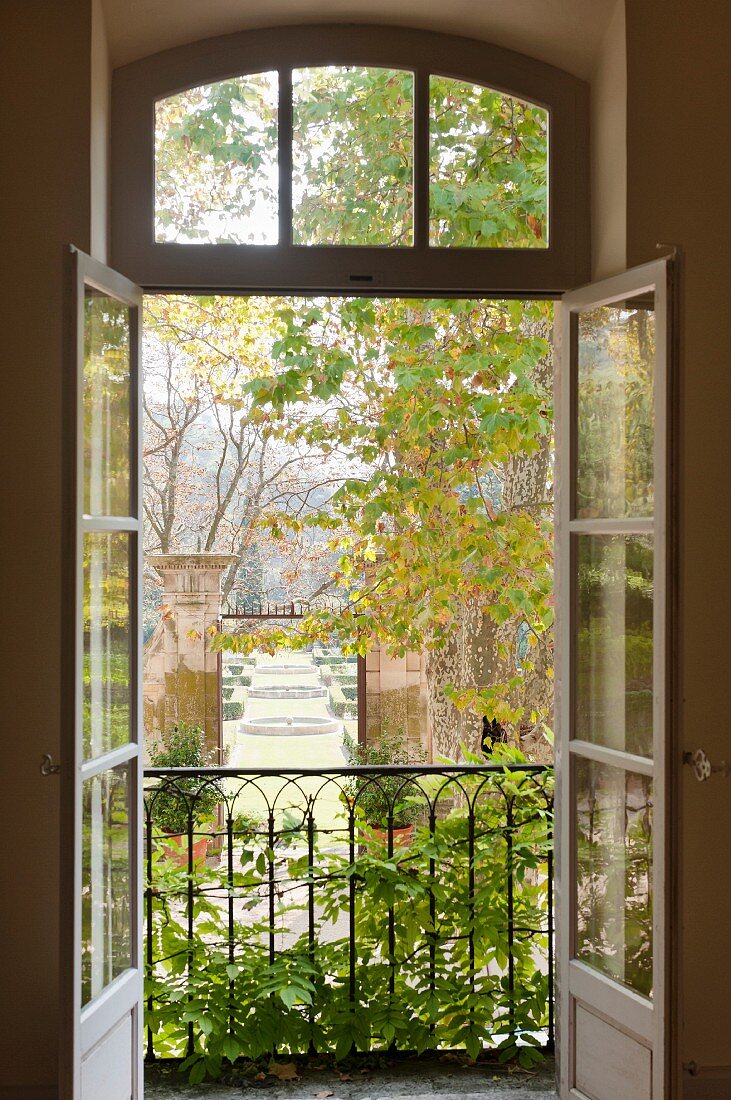View through open windows out to garden with topiary and fountains