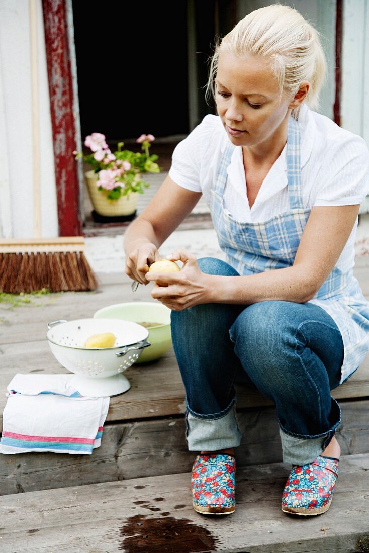 Frau beim Kartoffel schälen auf der Terrasse