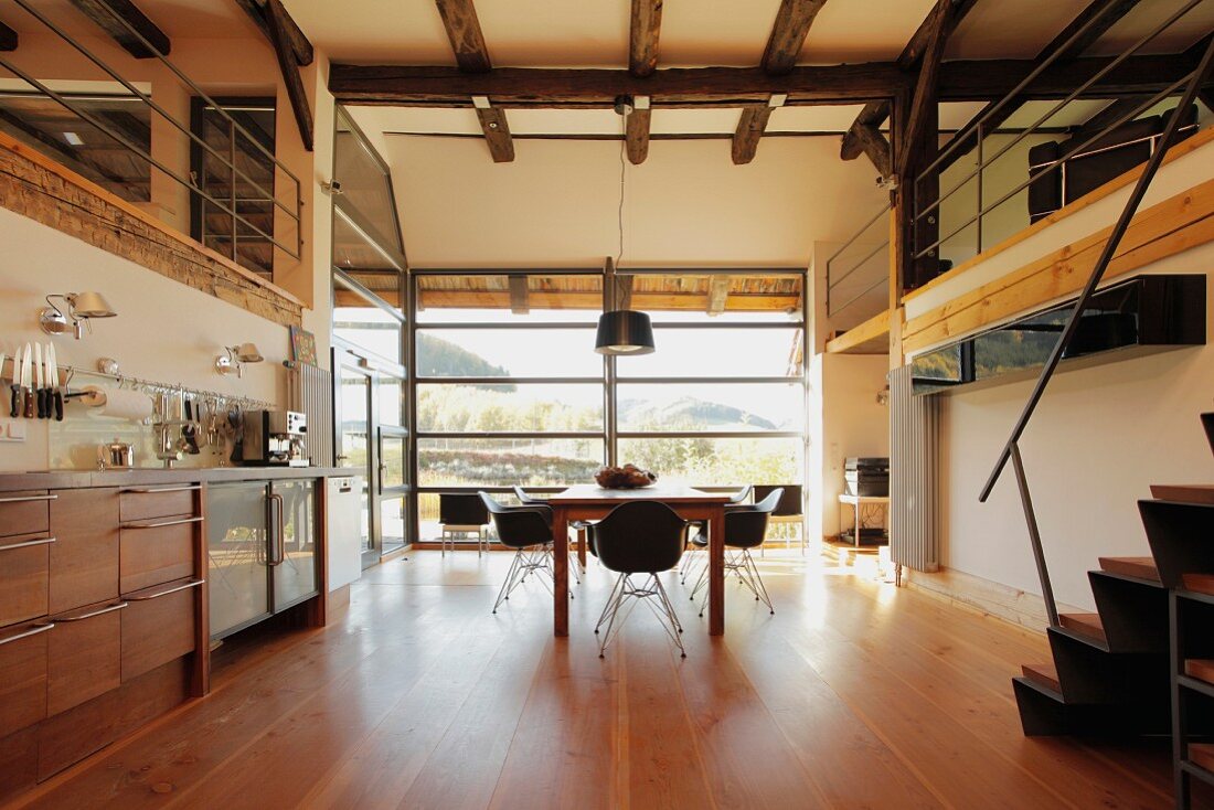 Open-plan kitchen with dining area in renovated farmhouse; panoramic window in background