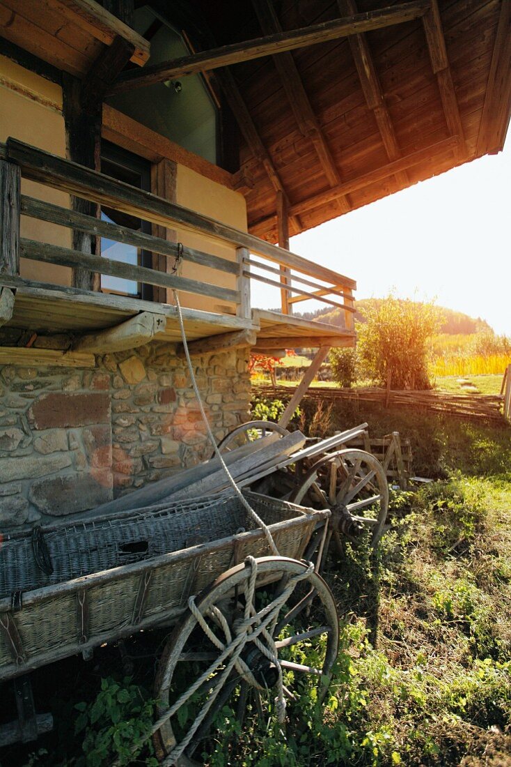 Alter Heuwagen vor Bauernhaus mit Balkon in ländlicher Umgebung