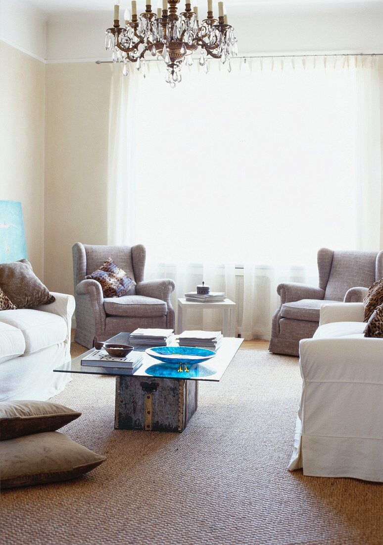 Hellgraue Sessel und Sofa um selbstgebautem Couchtisch in schlichtem Wohnzimmer