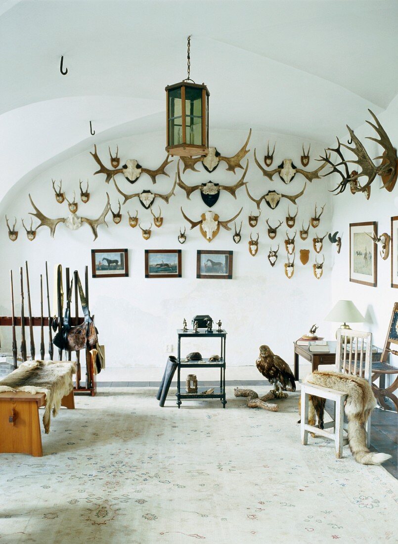 Various antlers on walls and hunting equipment in foyer with vaulted ceiling