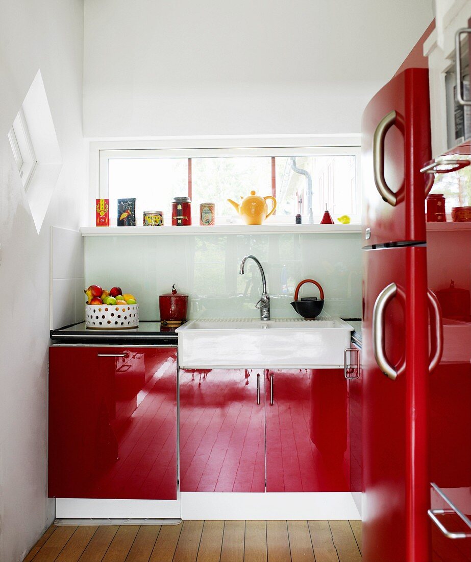 Kleine Küche mit glänzend roten Fronten und Fensterschlitz