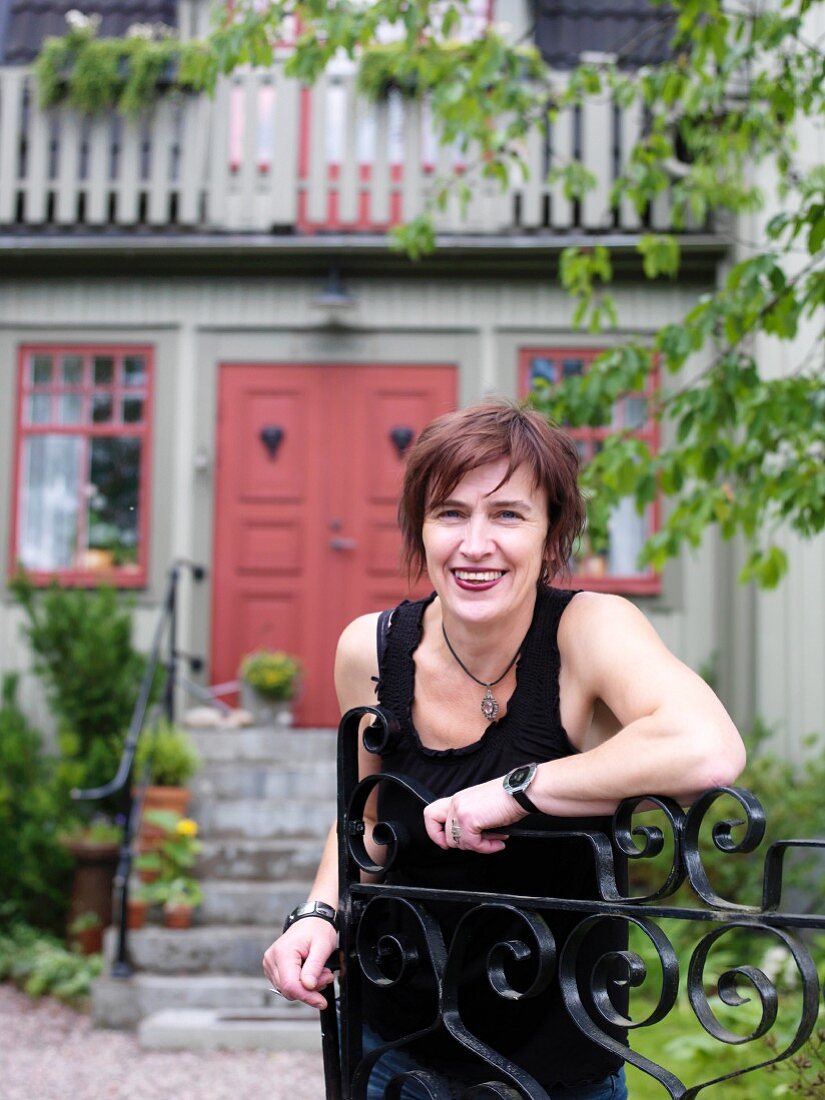 Woman leaning against a gate, Sweden.