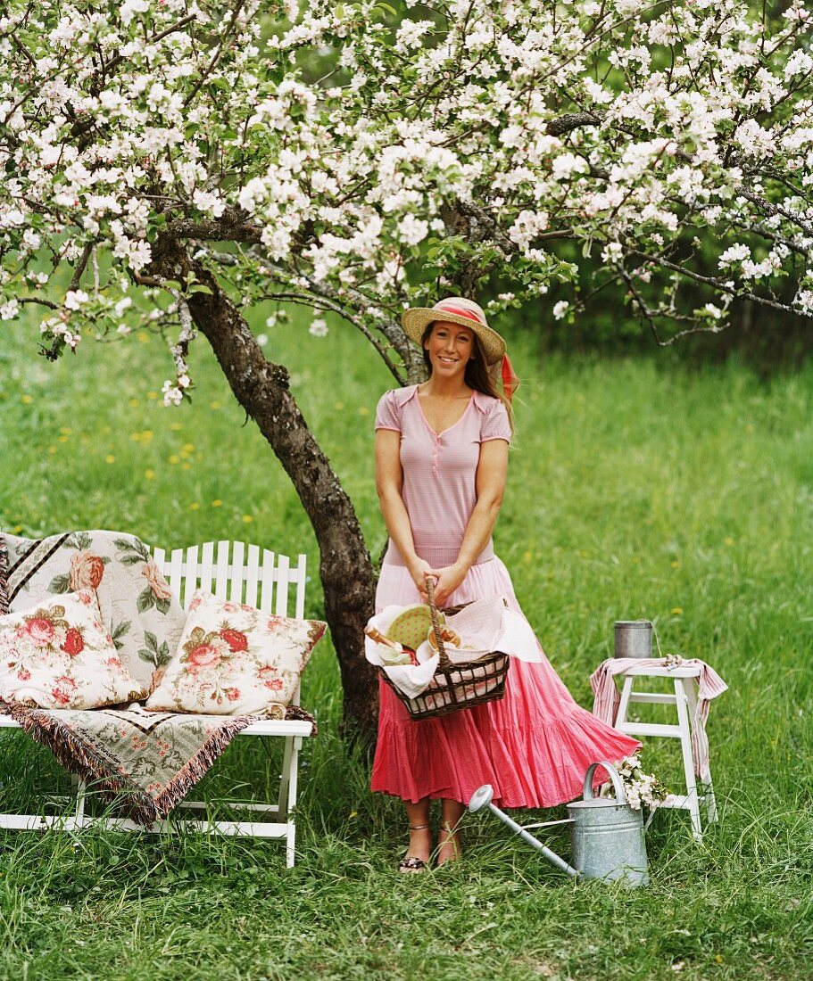 Junge Frau mit Strohhut unter blühendem Baum im Garten