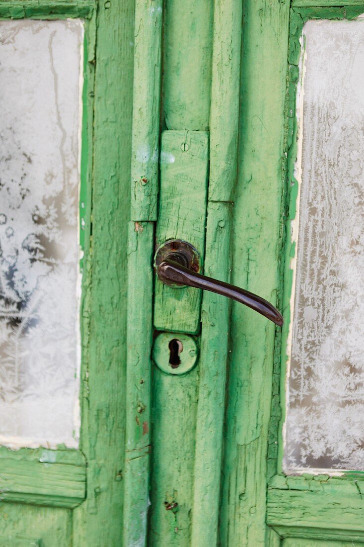 Alte grüne Holztür mit vereisten Fensterscheiben