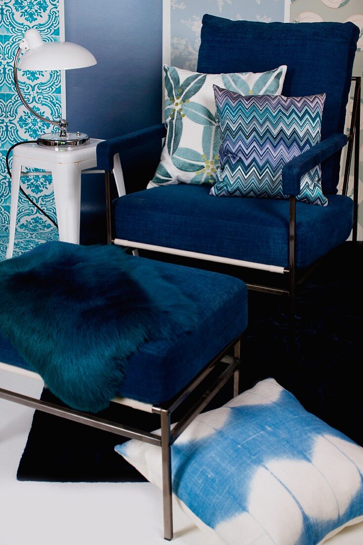 Armchair with blue upholstery, matching footstool and scatter cushions