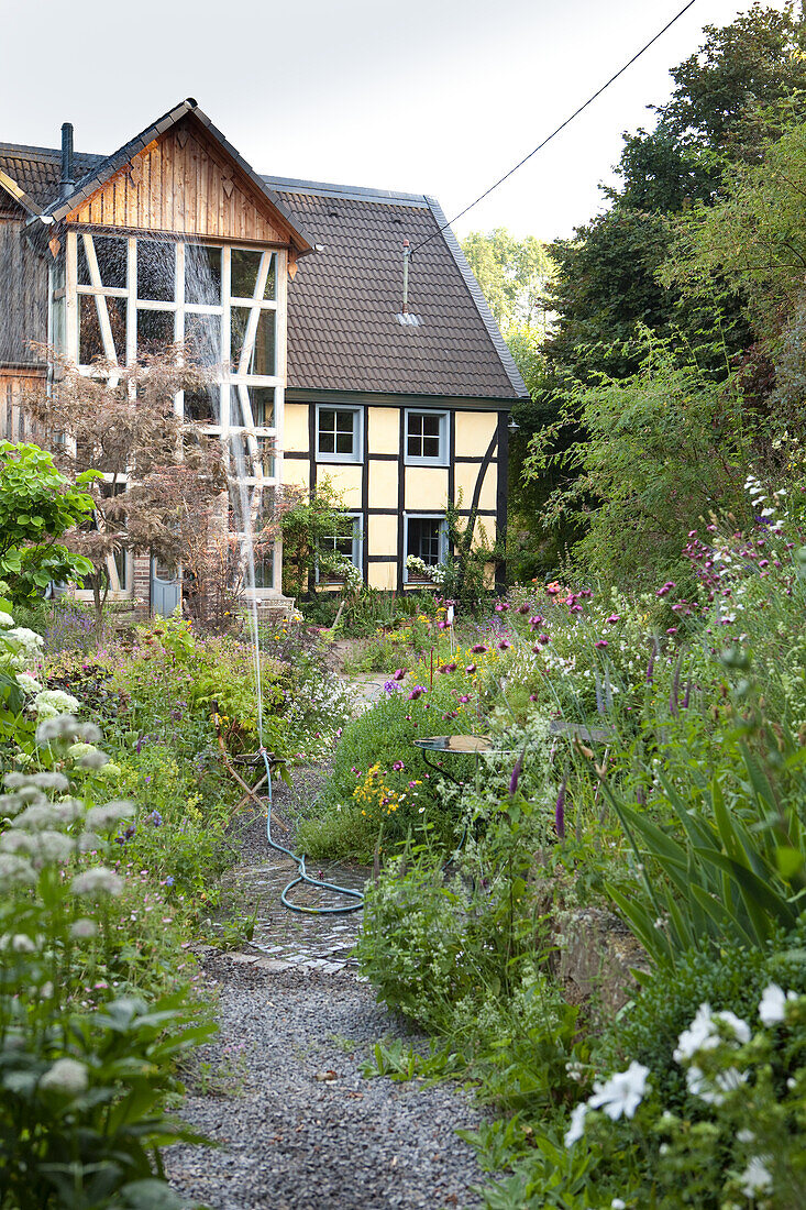 Blühender Garten mit Bewässerung und Wohnhaus im Fachwerkstil
