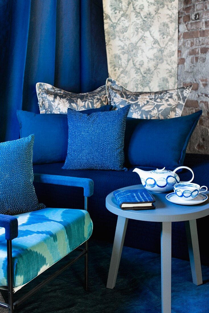 In Blautönen gestaltete Sitzecke mit Teekanne, Tasse und Notizbuch auf Beistelltisch