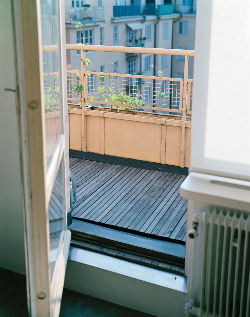 Sommerlicher Balkon mit offener Balkontür und mit Blick auf die Nachbarfassaden